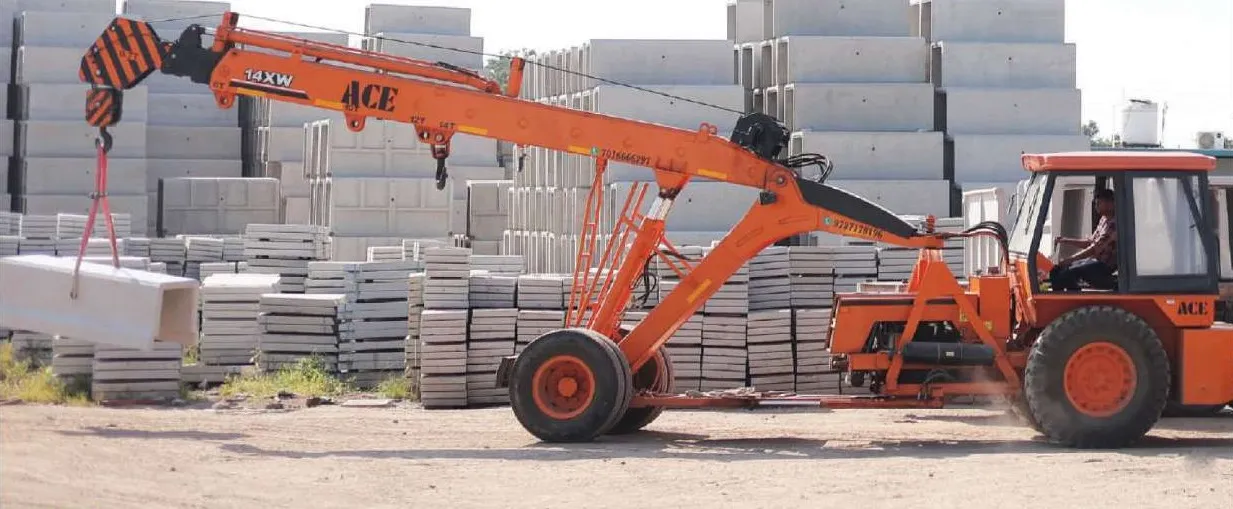 An orange ACE pick-and-carry crane lifts a precast concrete unit in the stockyard, with tall stacks of precast U-drains and cover slabs behind