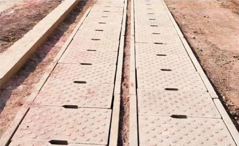 Two parallel lines of precast drains capped with studded cover slabs that have lifting slots