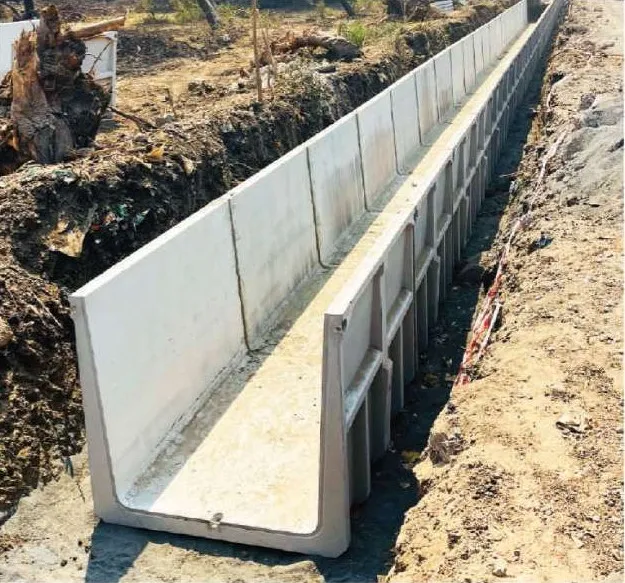 A long run of precast U-shape drain units with ribbed outer walls laid end to end in an excavated trench